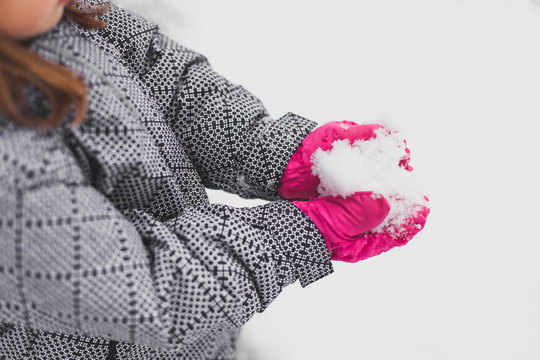 Smiling girl with bright pink hat plays in snow