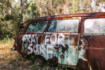Pray For Surf spray painted on an old rusted classic car