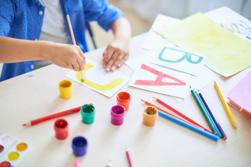 the child draws with a brush watercolor paints on paper the letter A