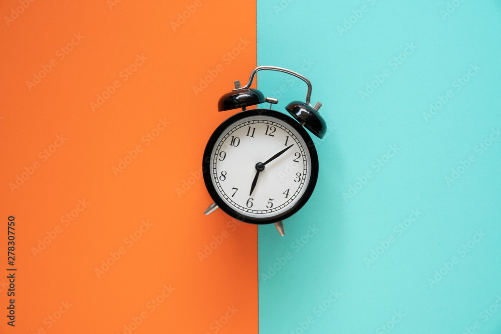 Wall mural retro alarm clock on color table background, vintage style