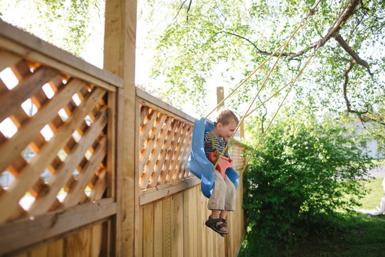Cute happy toddler boy enjoying backyard swing