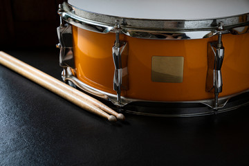 Drum stick and drum on black table background, close up for music concept