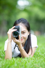 woman or girl photographer taking picture with retro camera lie down on grass, lifestyle and relaxing concept