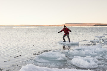 Man playfully balances and rides floating chunk of ice