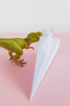 Dinosaur eating a paper airplane. Travel concept.