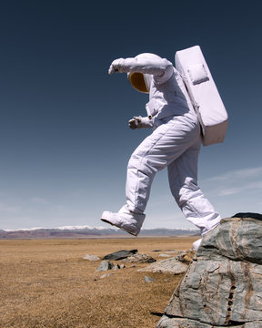 Astronaut jumping down from mountain
