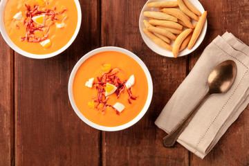 Salmorejo, Spanish cold tomato soup, shot from the top on a dark rustic wooden background with picos, typical breadsticks