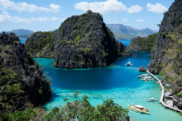 High view of paradise beach surrounded by rocks  with traditional boats.