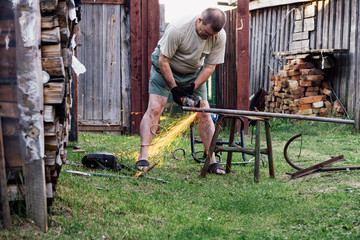 Mature man working with grinder saw outdoors.