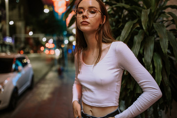 Portrait of beautiful young woman walking on the street by night