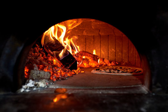 Pizza baking in flame of wood stove
