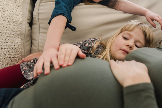 little girls touching  heir pregnant mother's belly