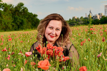 Plus sized woman in a black dress on a field of green wheat and wild poppies. Overweight fat woman. © Nikolay