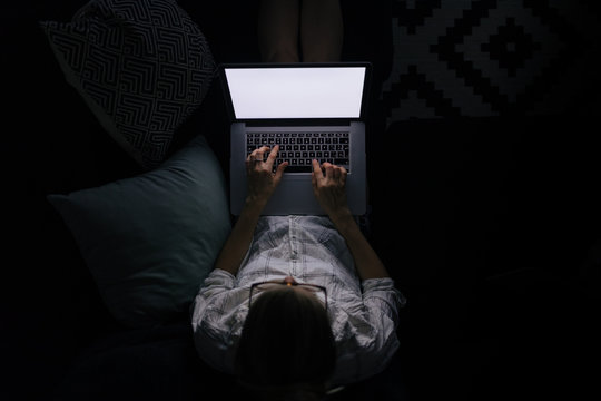 young woman with laptop on the sofa at night