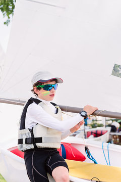 Young sailor sits on the side of his boat