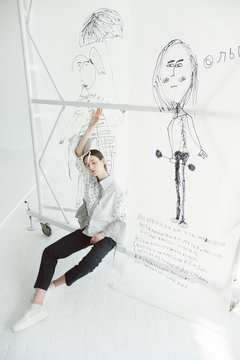 A girl by the backdrop with drawings.