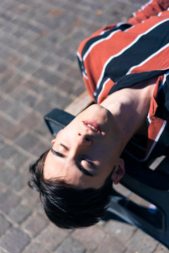 Young Man Laying Down on a Bench in the Park Relaxing