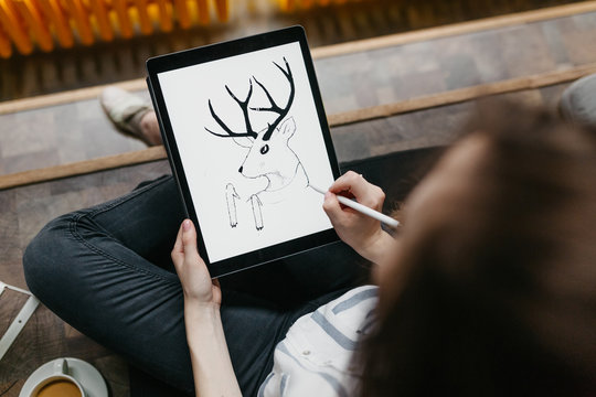 Brunette woman drawing on a tablet in the offce