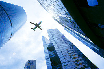 Fototapeta na wymiar Airplane flying over business skyscrapers. Business and transport, transportation, travel concept. Business trip background.