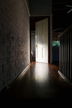 Light from a room illuminates a door in a dark hallway