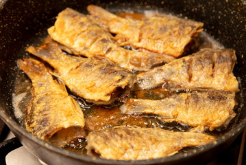 Fried fish in a pan in the kitchen