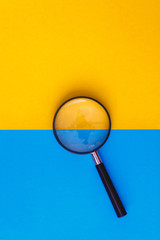 Magnifier lies on yellow and blue background. View from above. Flat lay. Copy space - 278315100