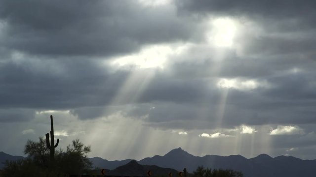Pan right, sun shines through clouds in desert landscape