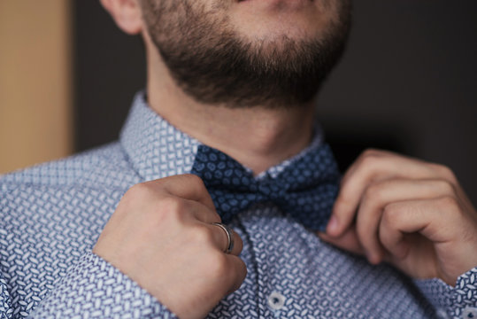 Close Up Portrait - Bearded Man Ties A Bowtie At The Collar