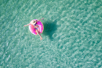 top aerial view of young woman enjoy swimming on floating inflatable tube in sea with cleared...