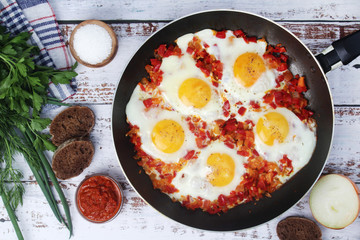 Shakshouka with five cooked eggs on top of tomato sauce in cast iron skillet