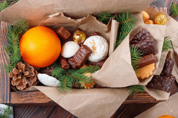 Delicious sweets, chocolates, cookies and oranges for gifts in  wooden box on  vintage table