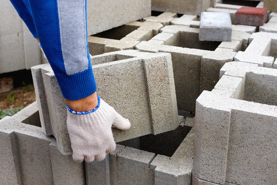 Worker loads cinder blocks  from cement slurry for construction
