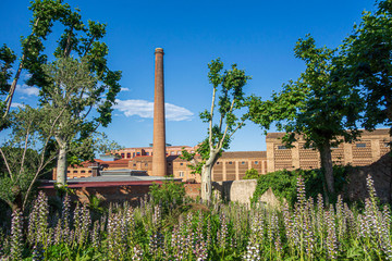 Chimney and industrial area enclosure of company town, Colonia Guell, Catalonia, Spain.