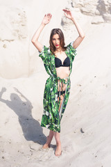 Obraz na płótnie Canvas Beautiful young woman walking on the beach, green desert wear.