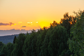 sunset from the window from the fifth floor. The sun illuminates the forest and the road.