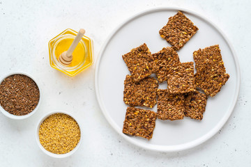 Golden and brown flax seeds and honey crackers on white stone background. Healthy raw vegan gluten free food concept.
