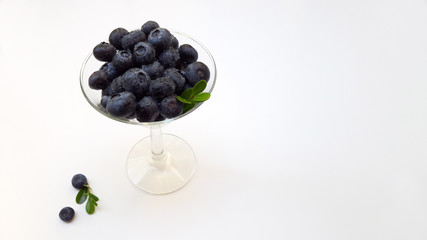 Fresh raw organic blueberries with leaf in in a glass wine glass