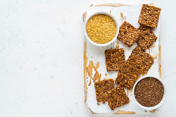 Golden and brown flax seeds and honey crackers on white stone background. Healthy raw vegan gluten...