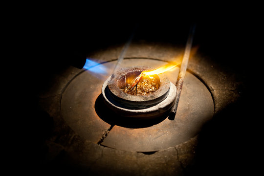 melting golden metal in furnace with fire for making jewelry - Powered by Adobe