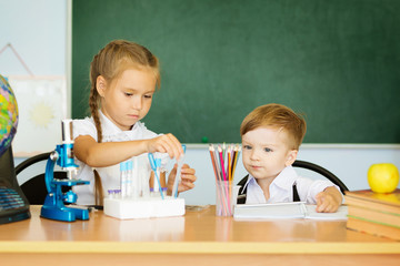 Knowledge is always yours. Cute Little girl helping her younger brother at classroom in school or pre-school