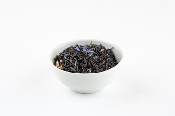 Dry black tea with blue flowers leaves in white bowl