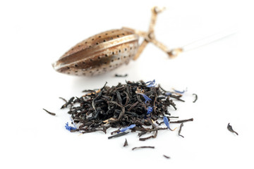 Dry black tea with blue flowers leaves and metal tea spoon on white background