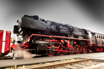 Alte historische Eisenbahn Dampflok in Bahnstation beim Betanken mit Kohle und Wasser