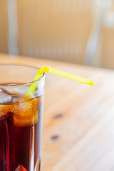 Icy cold beverage in a glass, close-up view. Glass of cool fizzy drink with ice on a wood table, vertical shot