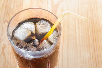 Icy cold beverage in a glass, top view. Glass of cool fizzy drink with ice on a wood table, close-up shot