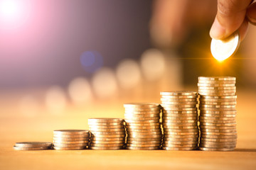 A hand putting money coins stack for save money concept. Money management is growing a business.
