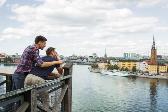 Two happy young friends looking at the amazing view of the city and sea