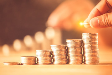A hand putting money coins stack for save money concept. Money management is growing a business.