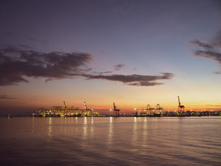 Fototapeta premium Shipping cranes at a port by the sea looking like metal giraffes