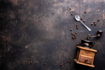 Old coffee grinder with spoon and coffee beans on dark background with copy space. Top view